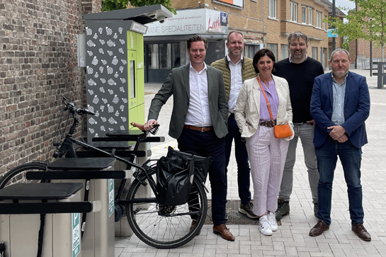 Gedeputeerde Tom Vandeput samen met burgemeester Liesbeth Van der Auwera samen met Hans de Raeve van Telloport bij de slimme fietsenstalling aan het Vrijthof in Bree